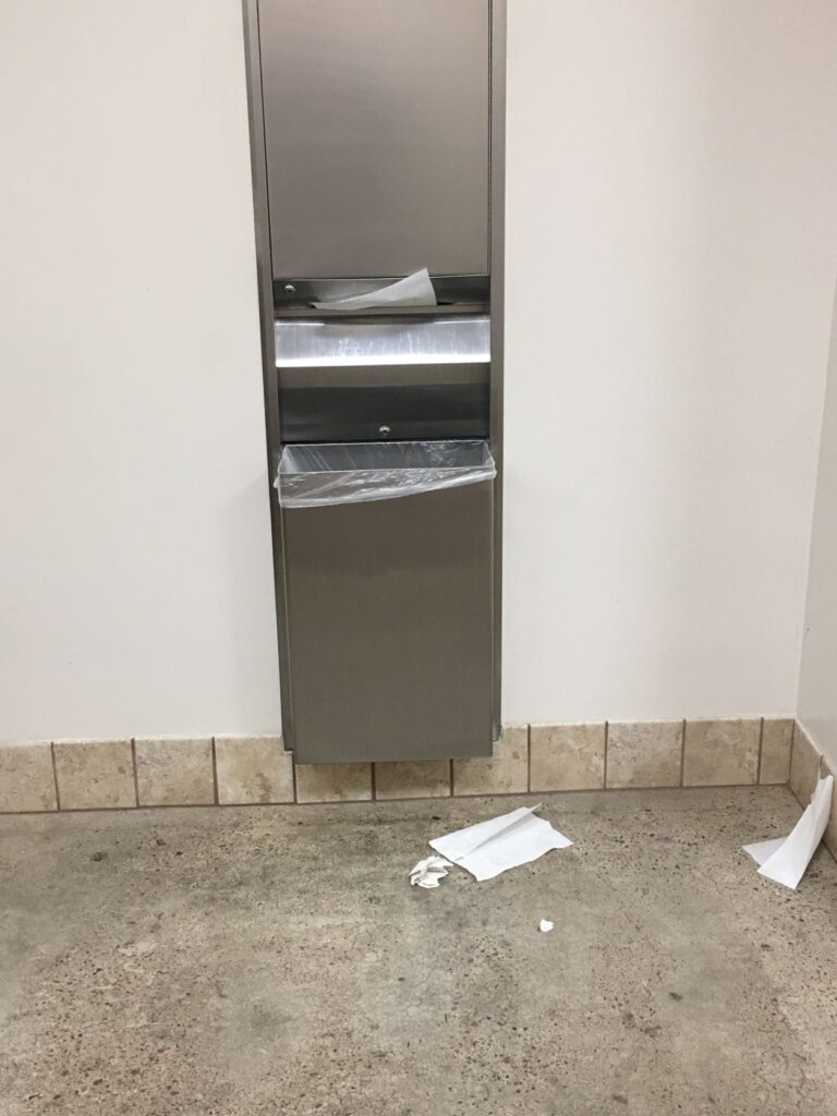 Trash on the floor right next to a trash can. 